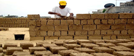 A person in a yellow hard hat building a wall

Description automatically generated